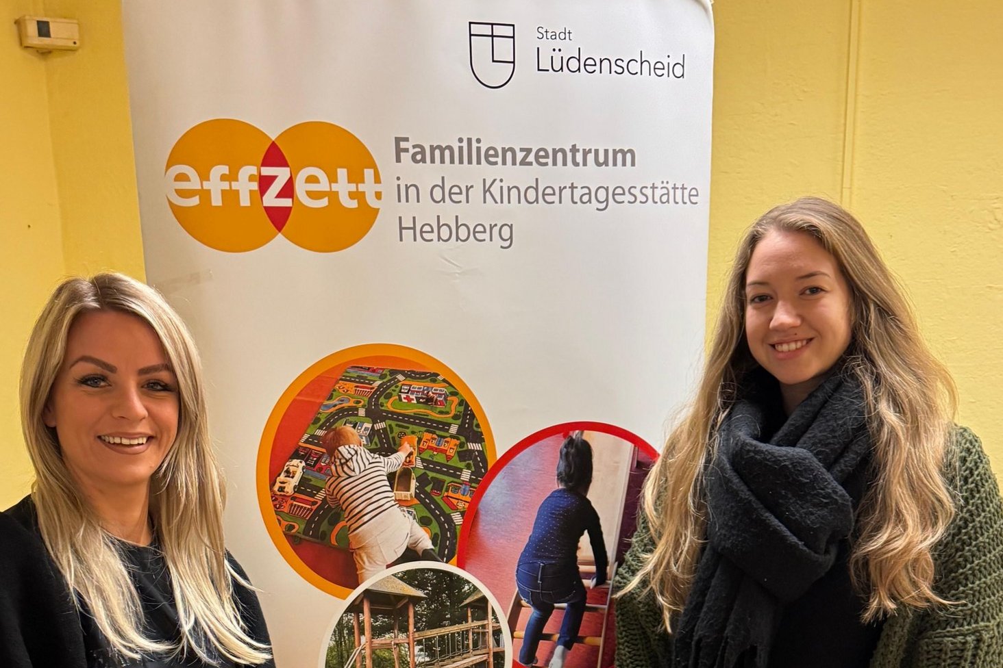 Zwei Mitarbeiterinnen neben einem Plakat-Austeller des effzett Familienzentrums