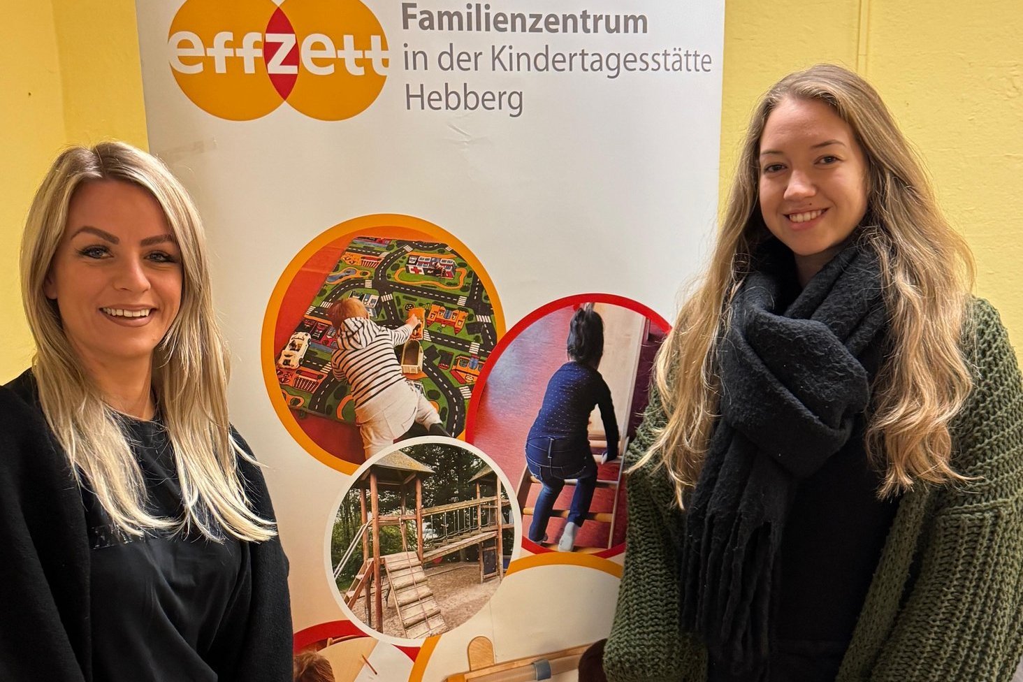 Zwei Mitarbeiterinnen neben einem Plakat-Austeller des effzett Familienzentrums