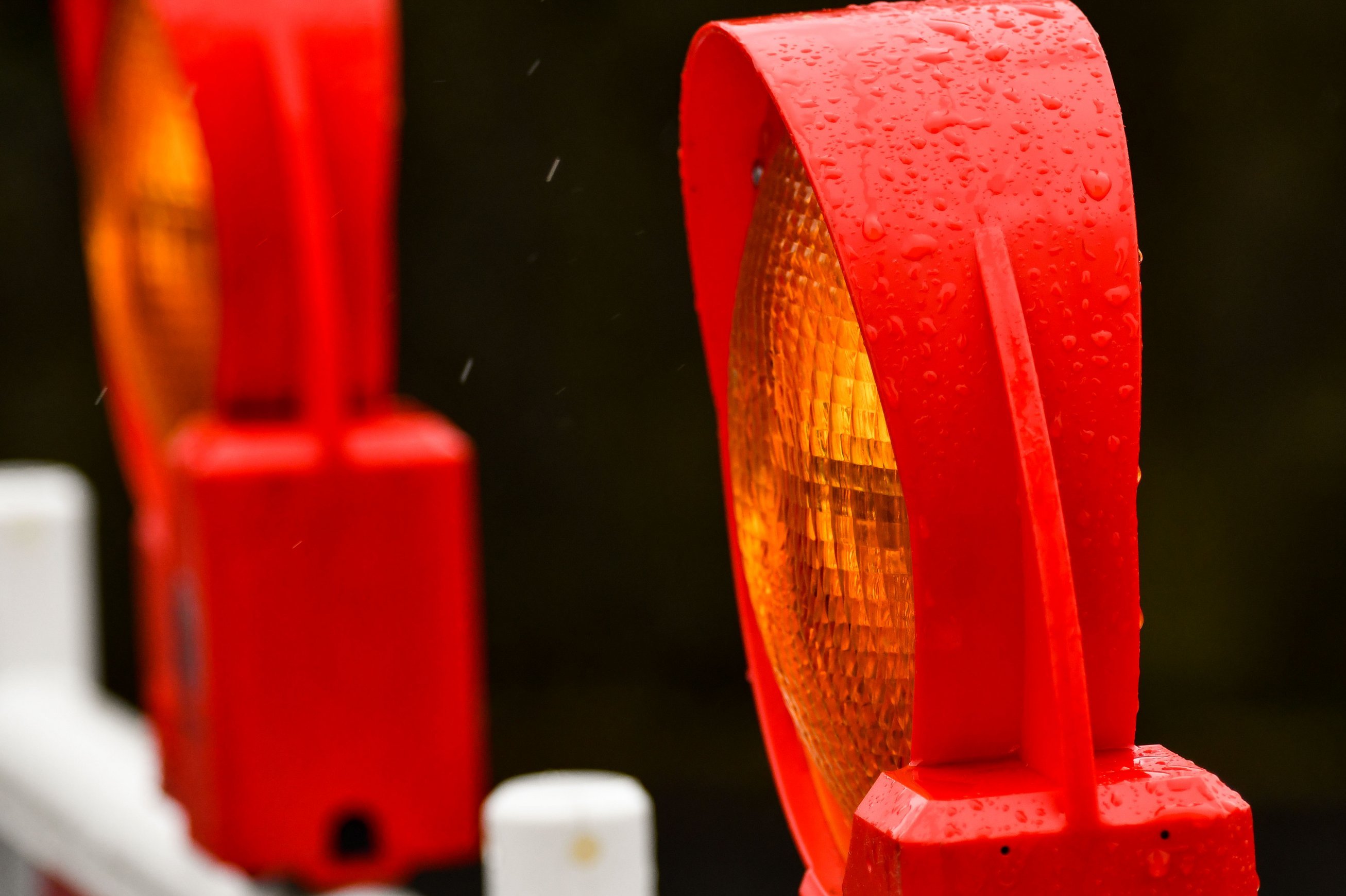 Ein Warnleuchte auf einer Baustellenabsperrung in Großaufnahme, im Hintergrund eine weitere Leuchte.