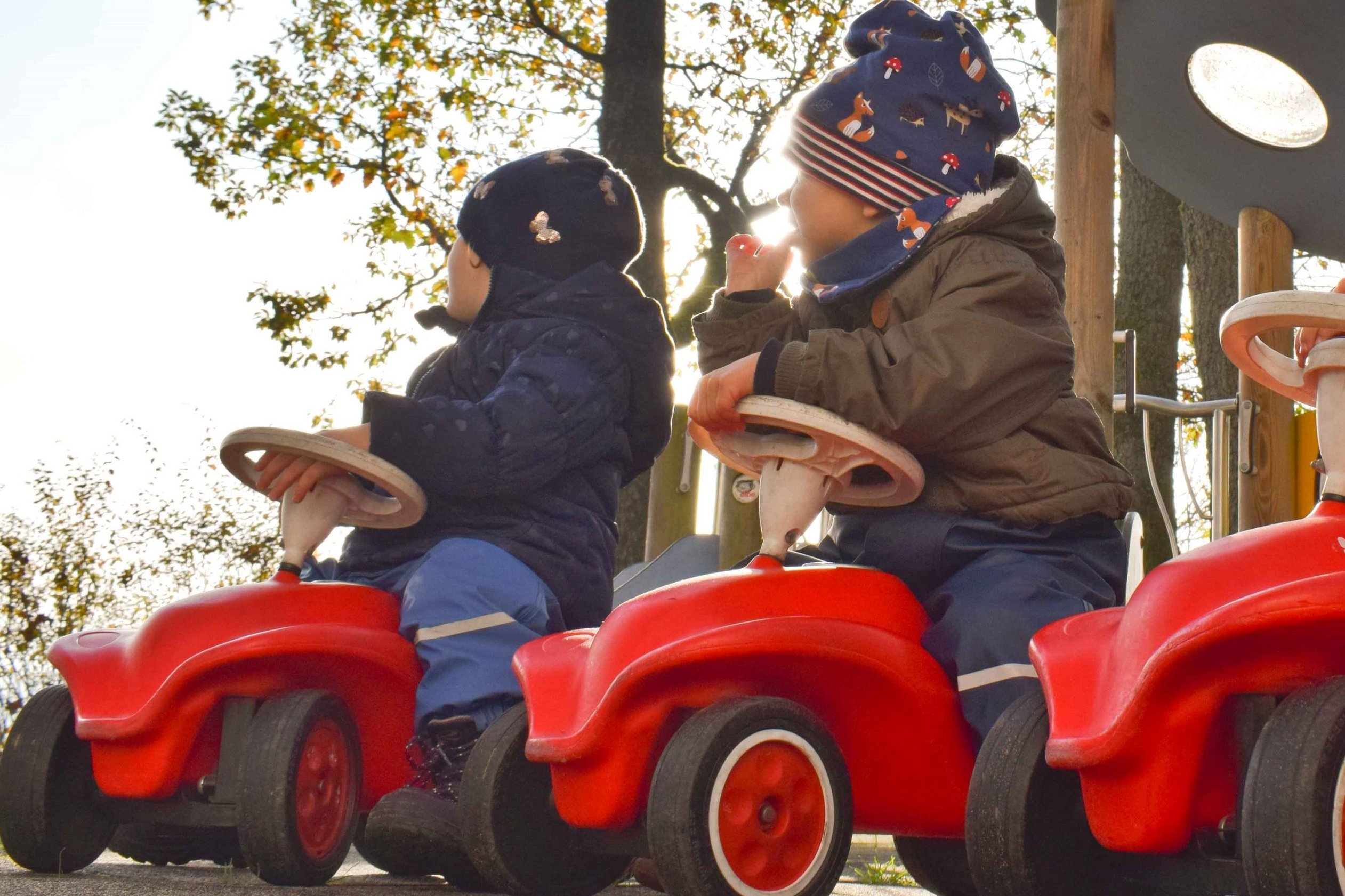 Zwei Kinder auf roten Bobbycars