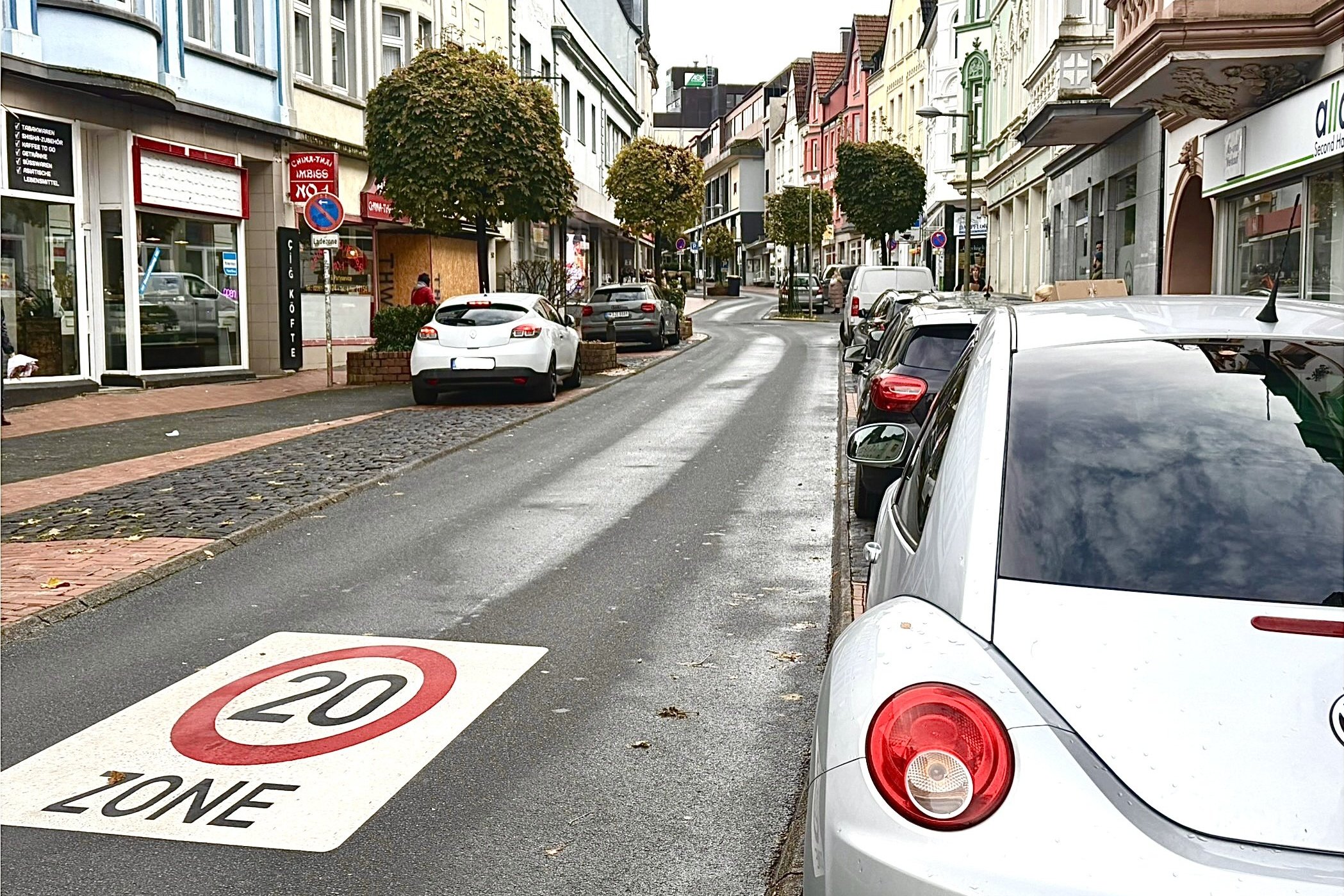 Blick auf die Knapper Straße. Neben der Fahrbahn sind auf beiden Seiten Fahrzeuge abgestellt.