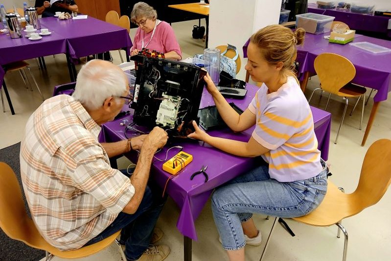 Ein älterer Mann und eine junge Frau reparieren zusammen einen defekten Gegenstand