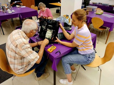 Ein älterer Mann und eine junge Frau reparieren zusammen einen defekten Gegenstand