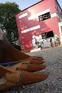 Eine Baggerschaufel - im Hintergrund das entkernte Gebäude der Grundschule Lösenbach.