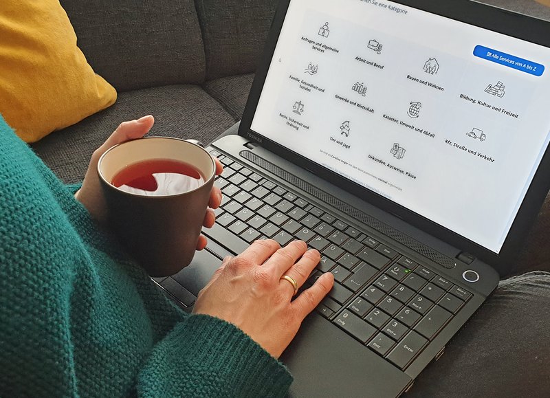 Person mit aufgeklapptem Notebook auf dem Sofa