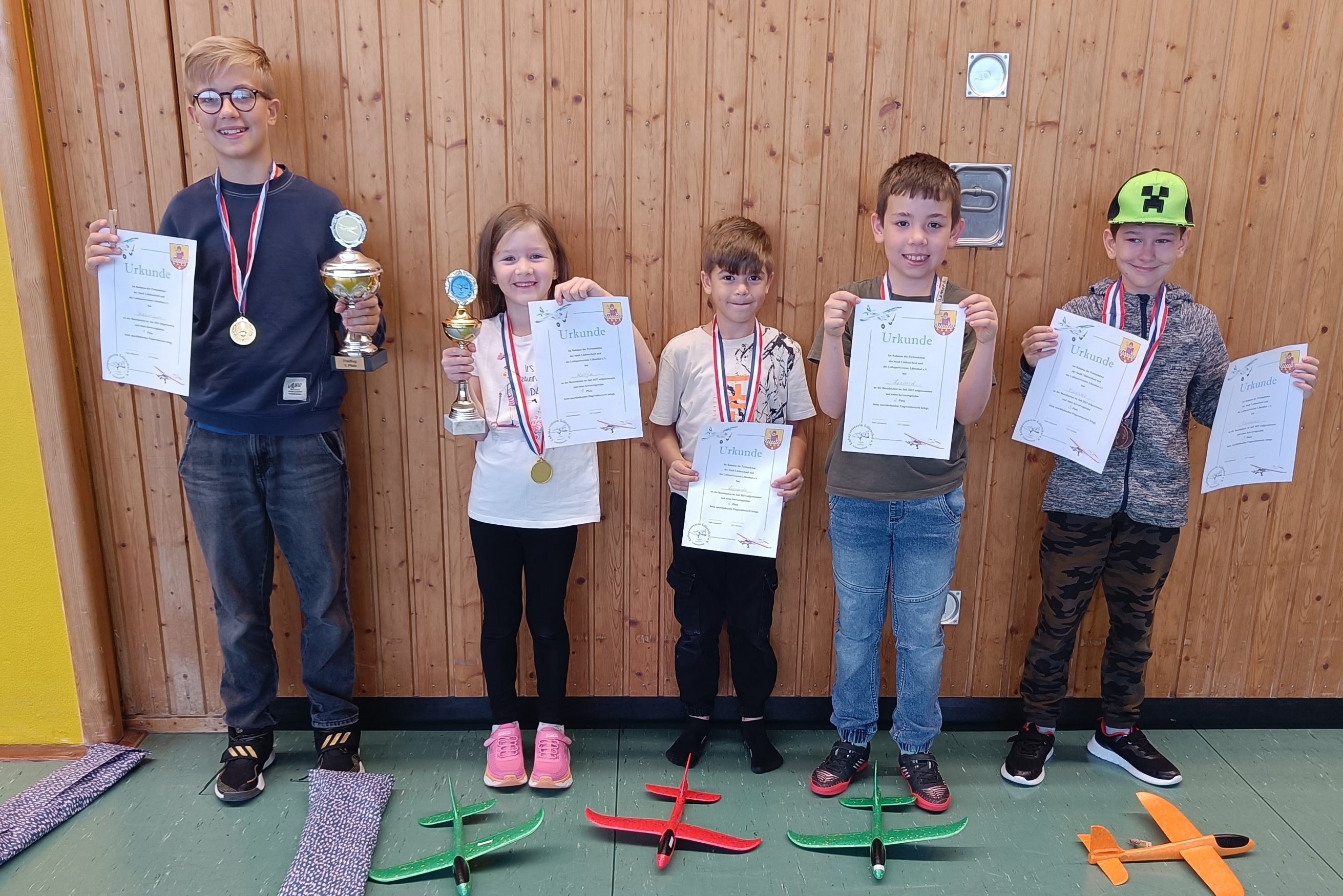 Kinder mit ihren gebastelteten Modellflugzeugen bei der Siegerehrung