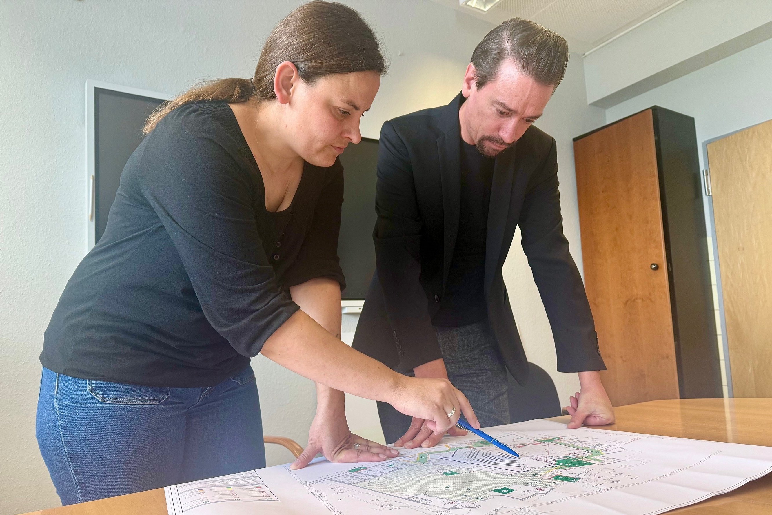 Sandra Kriewaldt und Dirk Lattemann betrachten einen Gebäudeplan und besprechen das weitere Vorgehen nach dem Asbest-Fund im Kulturhaus