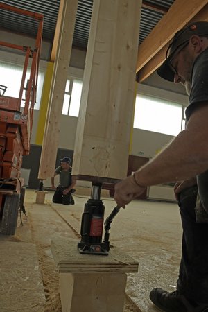 Ein Mann betätigt den Stempelheber der unter einem Holzbalken angebracht ist.