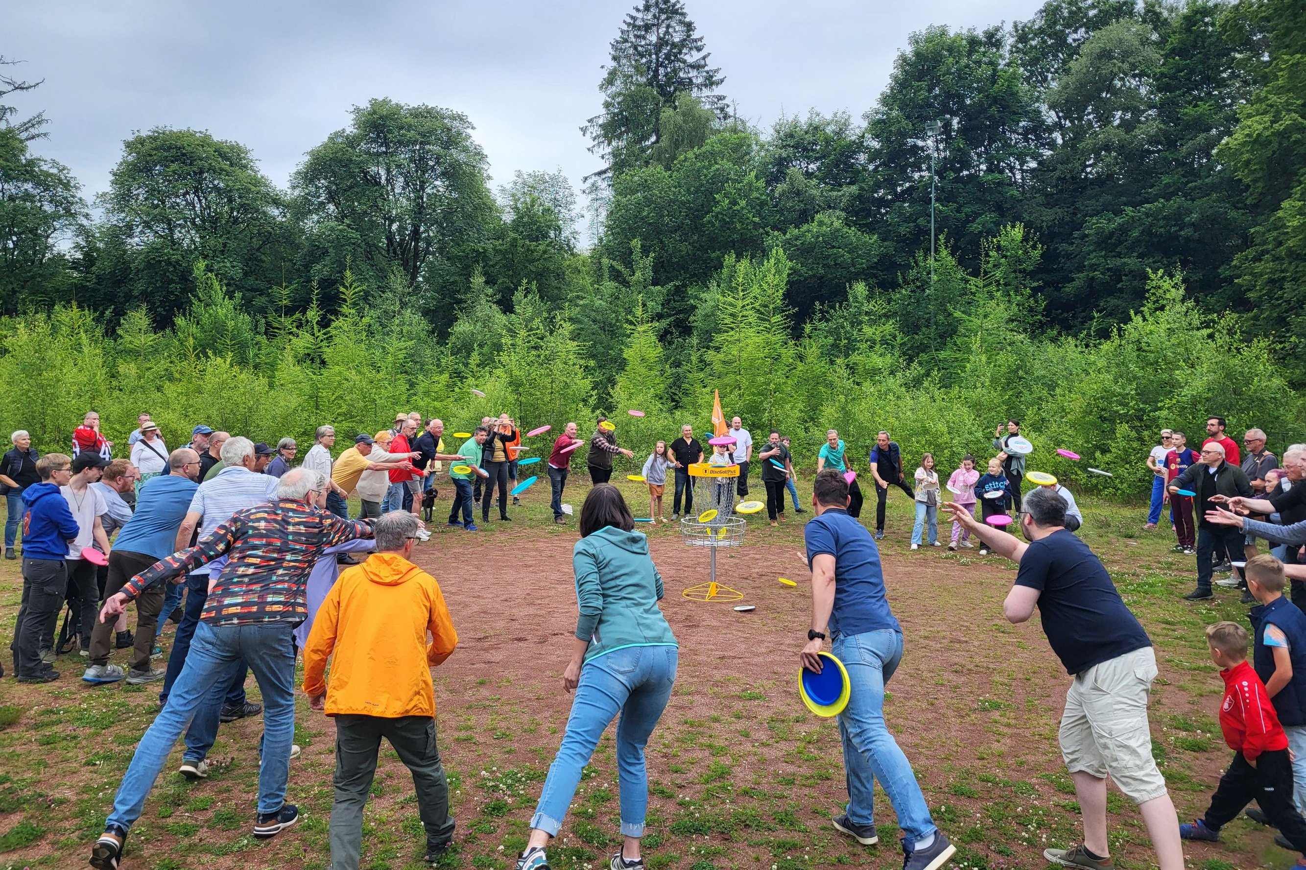 Viele Menschen werfen gleichzeitig eine Frisbee auf das Ziel in der Mitte