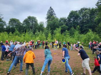 Viele Menschen werfen gleichzeitig eine Frisbee auf das Ziel in der Mitte