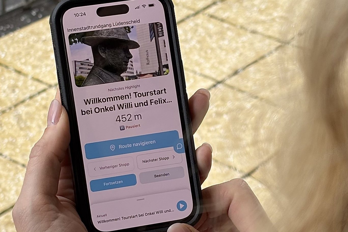 Eine frau hält ein Handy mit der geöffneten App in der Hand.