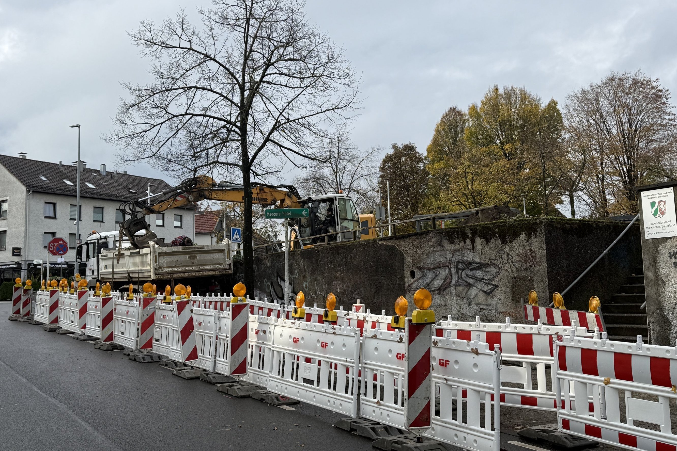 Die Sanierungsarbeiten an der Stützmauer an der Ecke Parkstraße/Winkhauser Straße haben begonnen. Absperrungen sind davor aufgebaut.