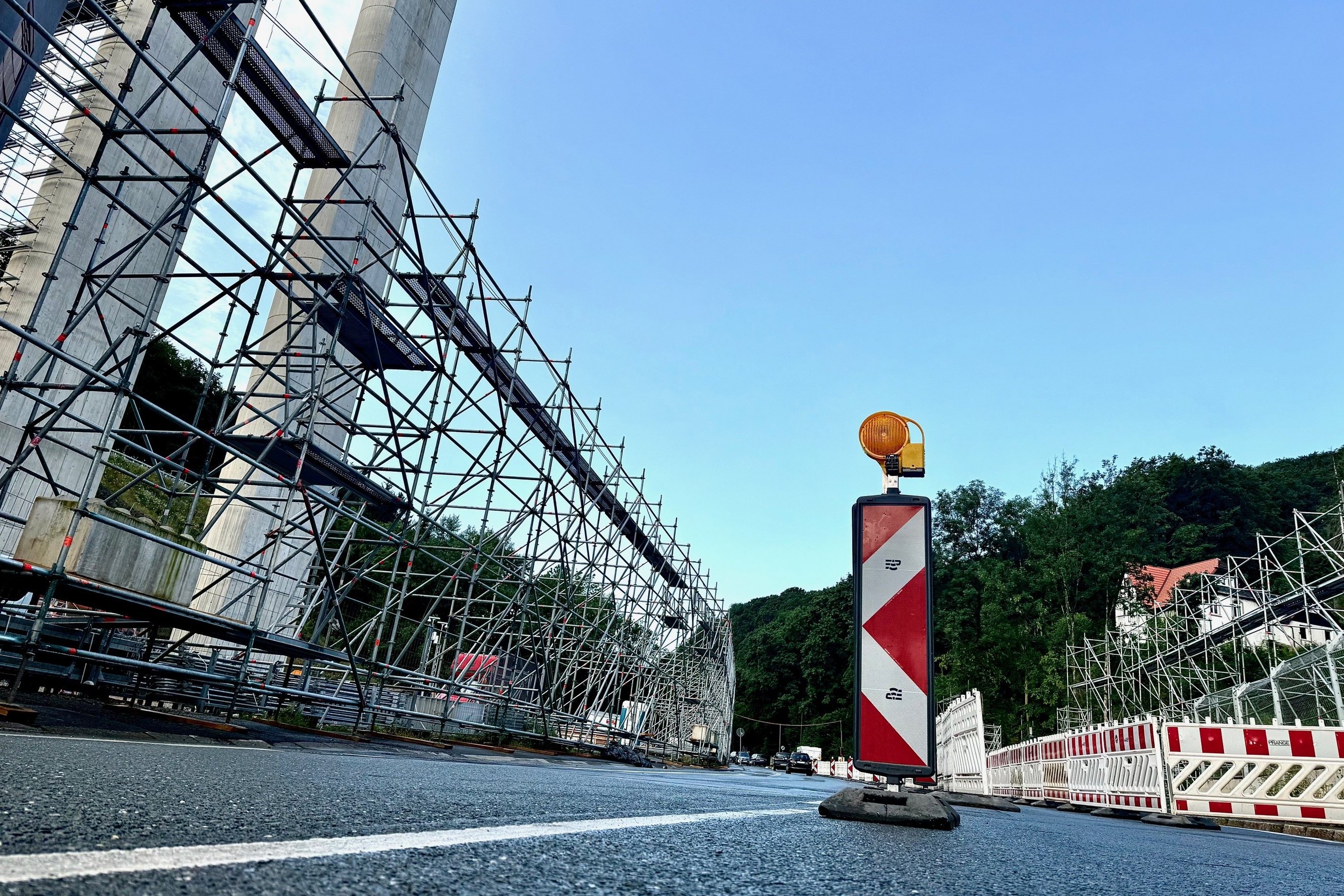 Auf der Altenaer Straße stehen Absperrungen. Links ist ein großes Stahlgerüst zu sehen.