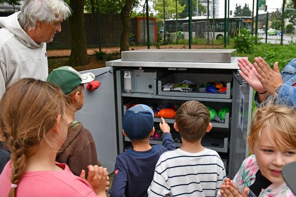 Dierk Gelhausen zeigt Kindern den Inhalt der Sportbox am Stadtgarten