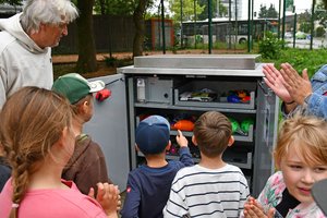 Dierk Gelhausen zeigt Kindern den Inhalt der Sportbox am Stadtgarten