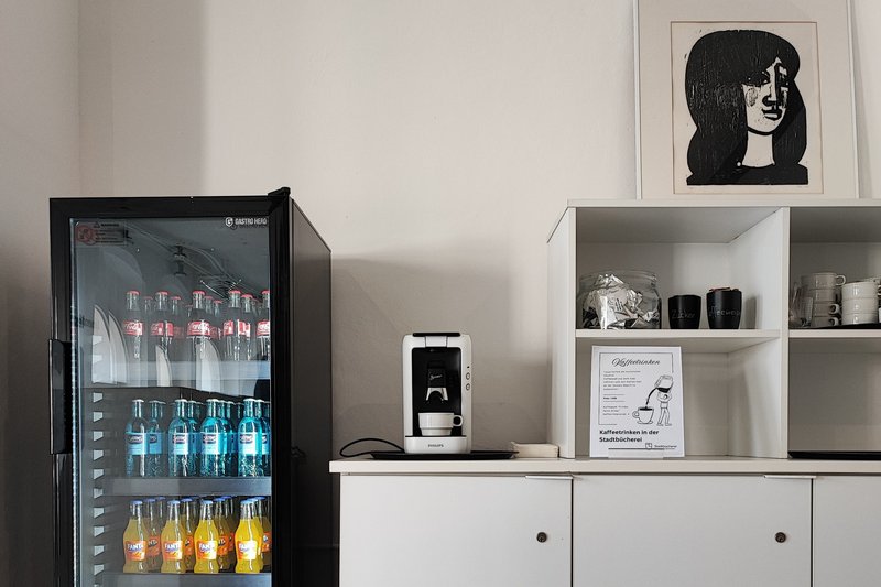 Ein Kühlschrank mit Kaltgetränken und ein Regal mit Kaffeemaschine