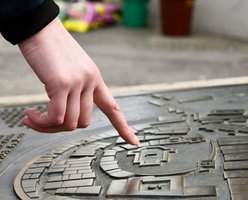 Hand zeigt auf eine Reliefplatte des alten Stadtplans