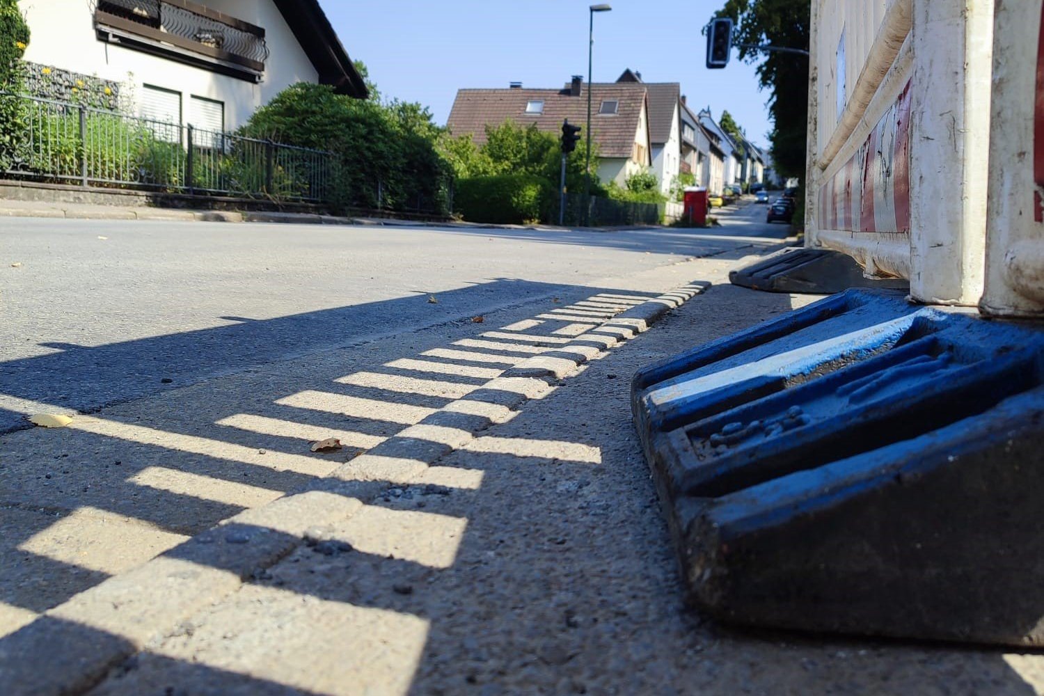 Blick auf eine erneuerte Fahrbahndecke aus einer niedrigen Perspektive. Rechts steht eine Baustellenbake.