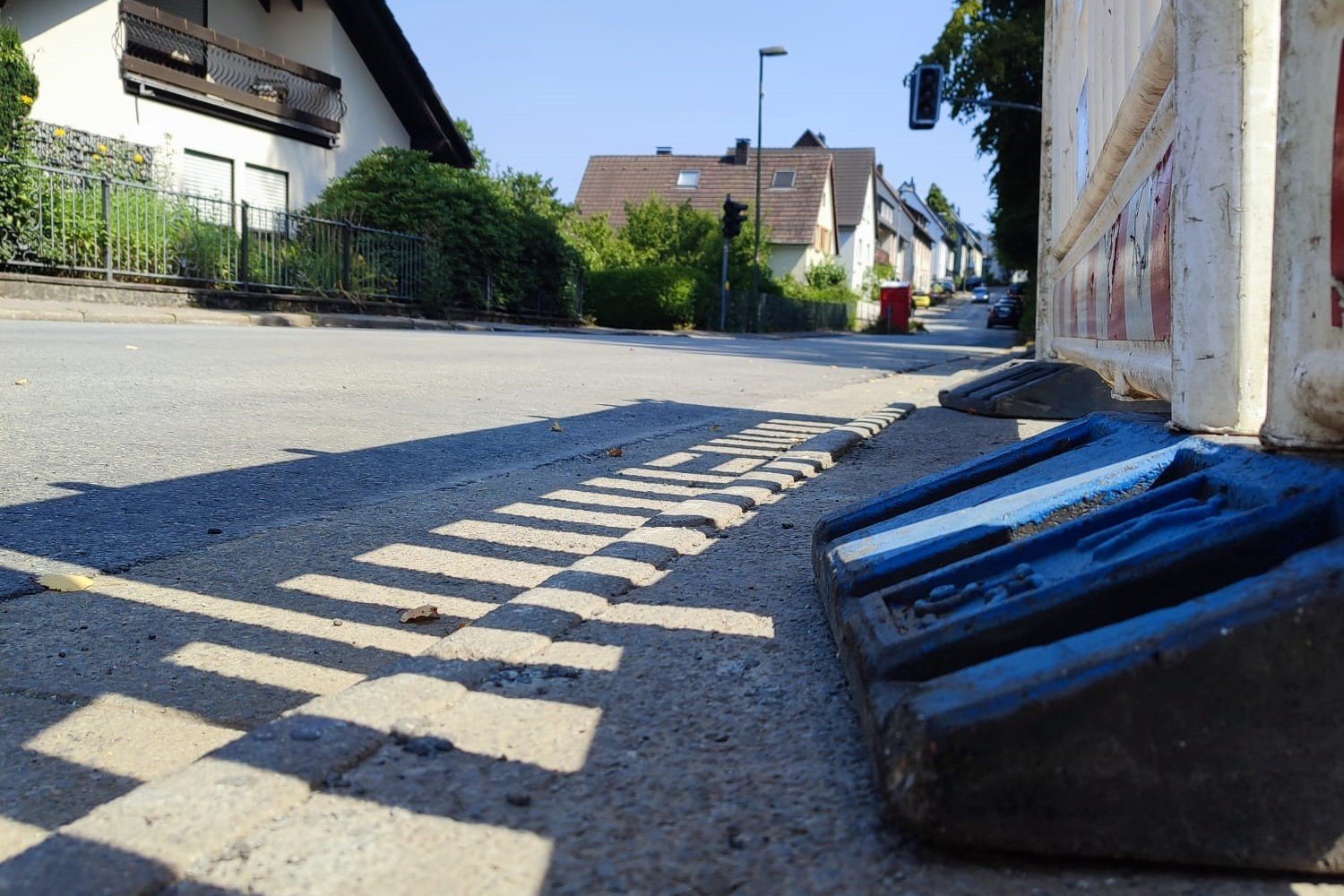 Blick auf eine erneuerte Fahrbahndecke aus einer niedrigen Perspektive. Rechts steht eine Baustellenbake.