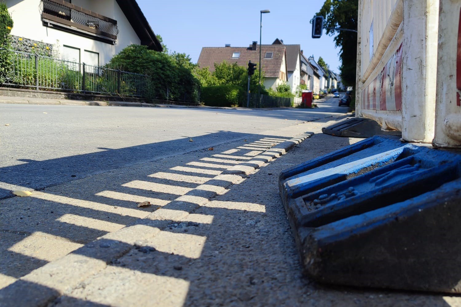 Blick auf eine erneuerte Fahrbahndecke aus einer niedrigen Perspektive. Rechts steht eine Baustellenbake.