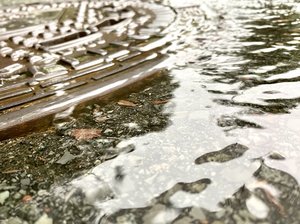 Ein überschwemmter Gully und Wasser auf der Straße