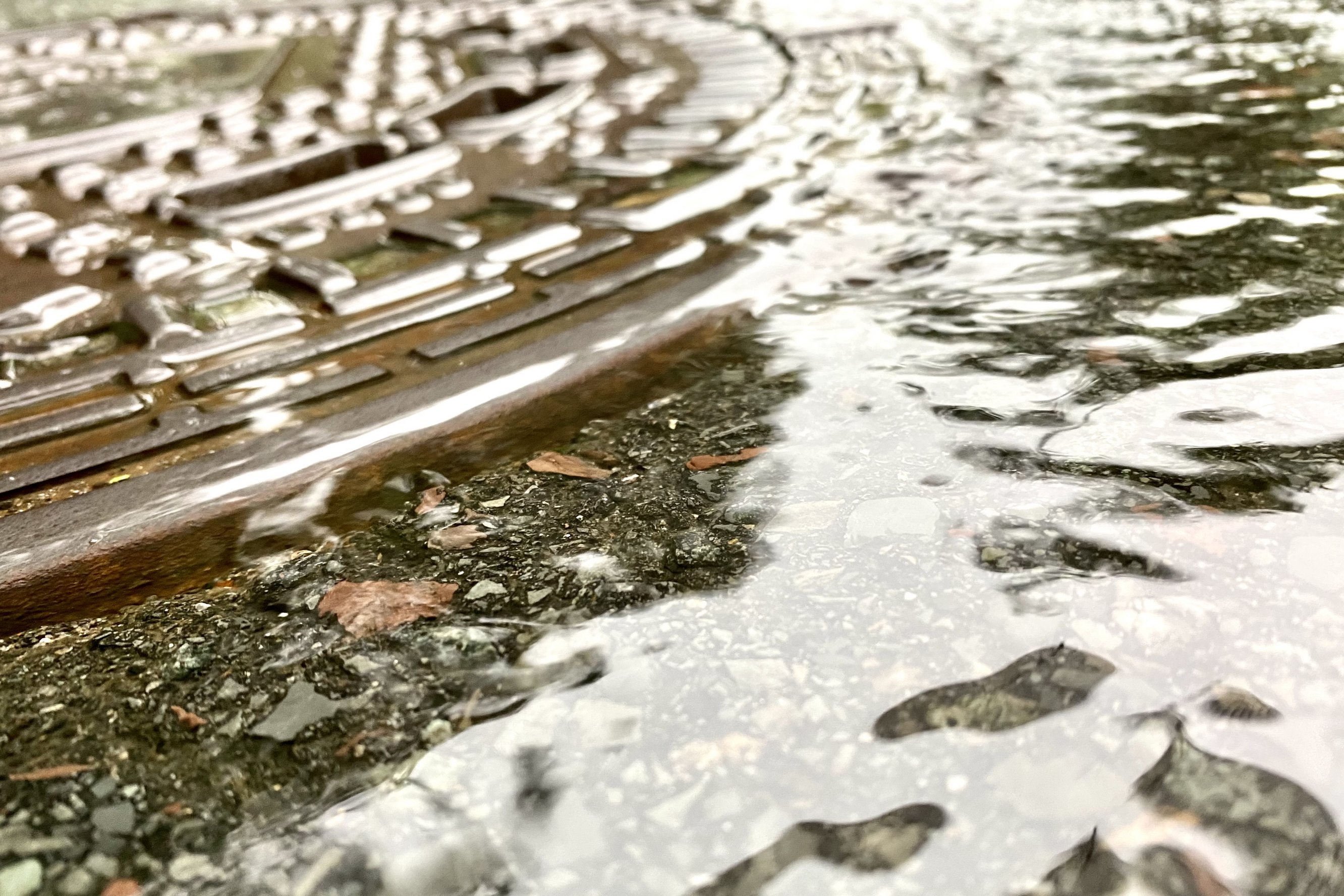 Ein überschwemmter Gully und Wasser auf der Straße