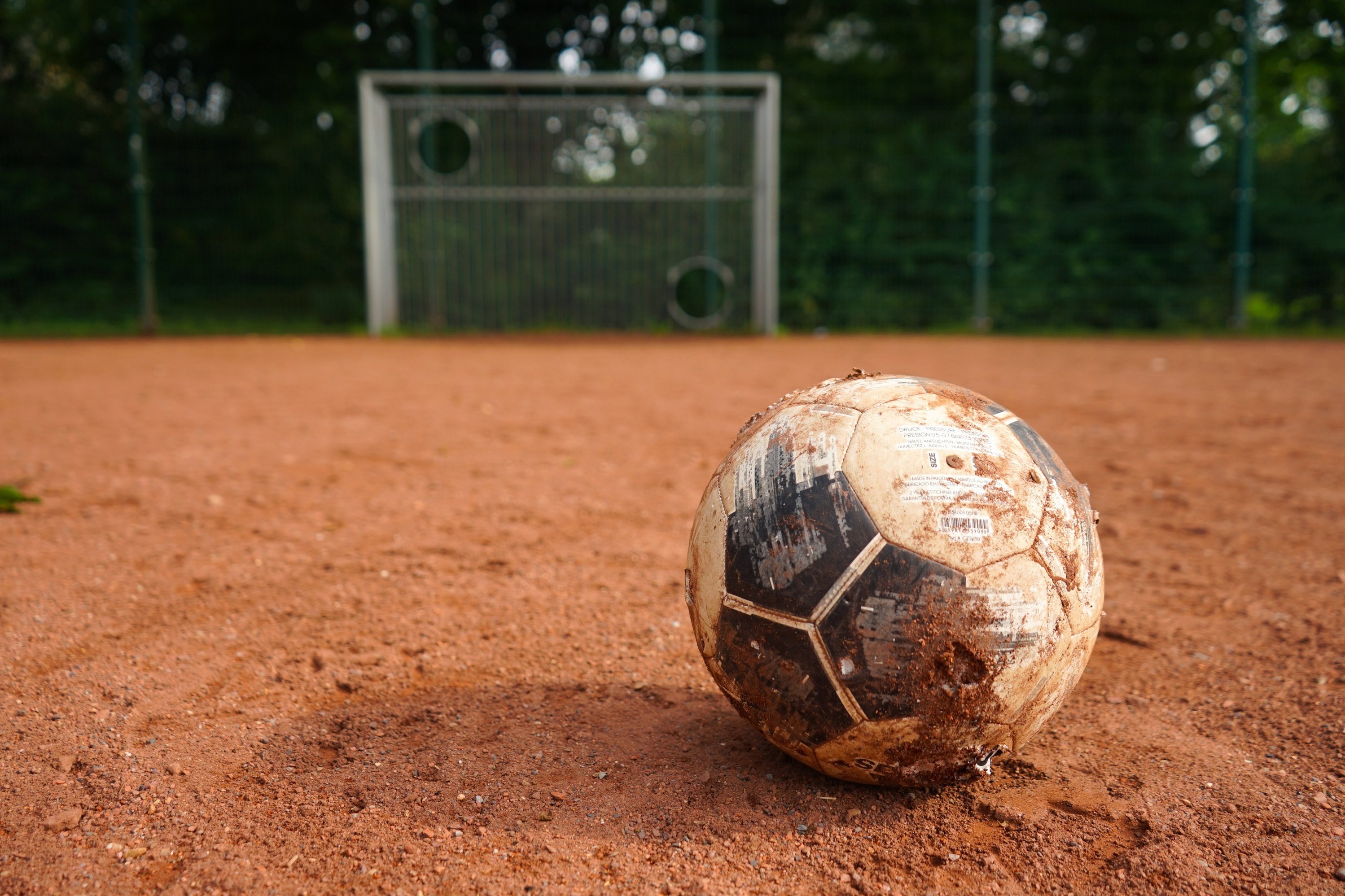 Ein Fußball liegt auf einem Ascheplatz