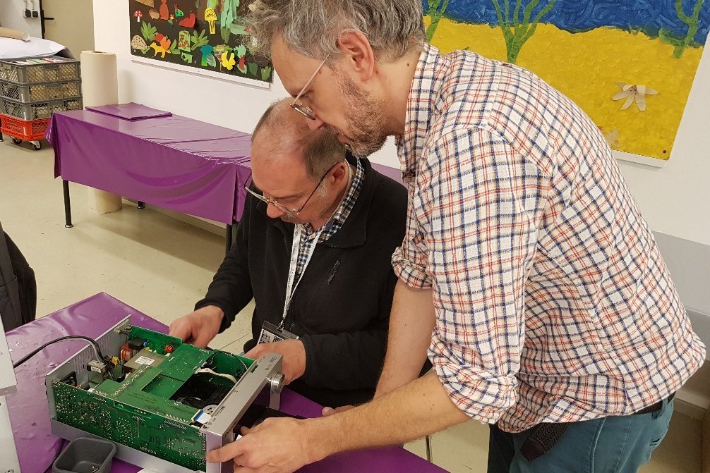 Zwei Männer arbeiten an einem defekten Gegenstand