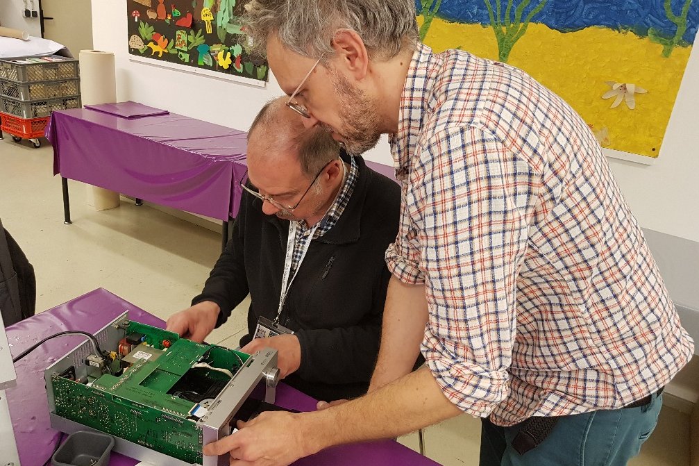 Zwei Männer arbeiten an einem defekten Gegenstand