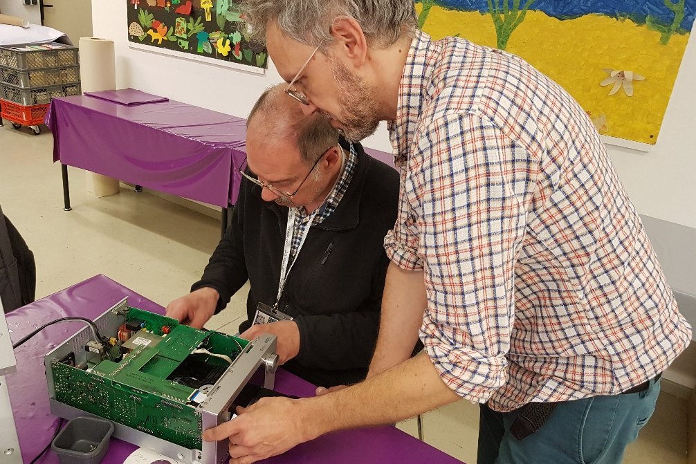 Zwei Männer arbeiten an einem defekten Gegenstand