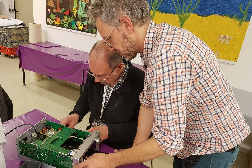 Zwei Männer arbeiten an einem defekten Gegenstand