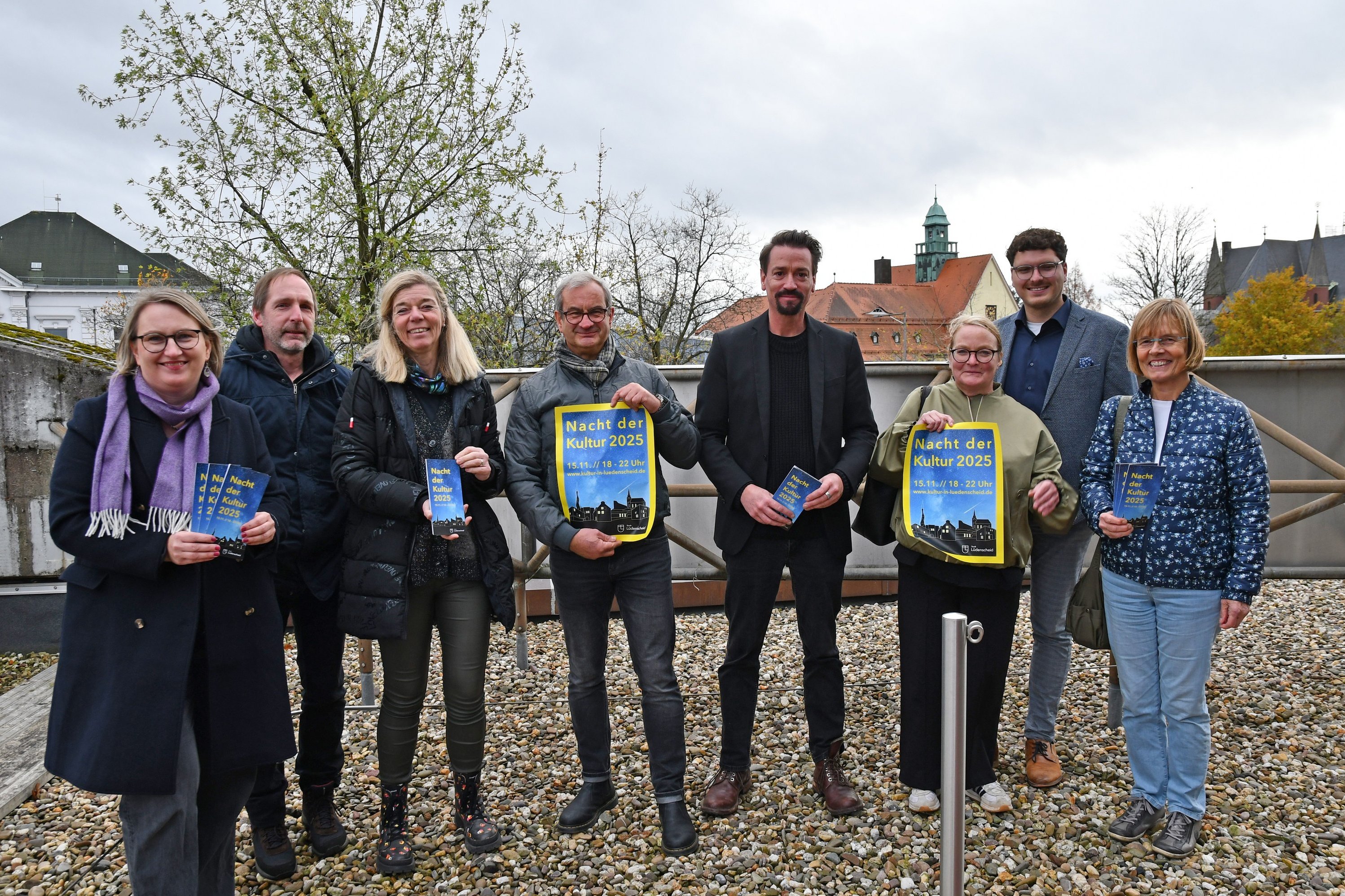 Vertreter des Kulturbeirats und der Stadt Lüdenscheid mit Plakaten und Flyern zur Nacht der Kultur auf dem Dach des Kulturhauses