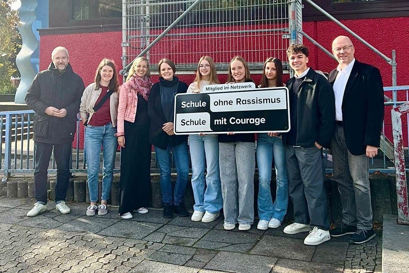 Die Mitglieder der BGL-Schülervertretung halten das Schild hoch, das inzwischen an der Außenfassade der Schule angebracht ist. Links davon die Lehrerinnen, die die Jugendlichen bei der Netzwerk-Arbeit unterstützen, rechts Schulleiter Dieter Utsch. Bürgermeister Sebastian Wagemeyer (links) gratulierte allen zur Aufnahme in das Netzwerk. 