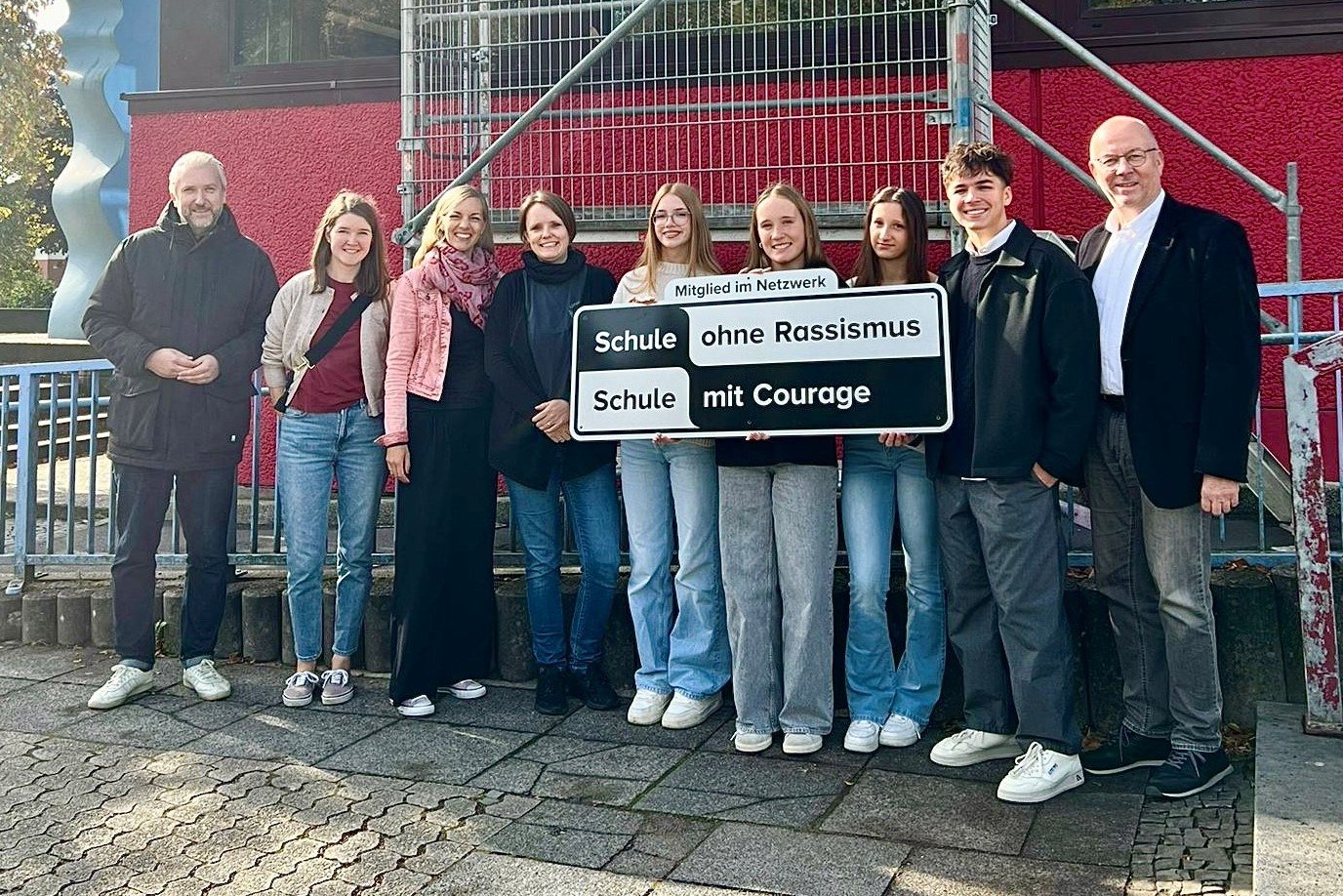 Die Mitglieder der BGL-Schülervertretung halten das Schild hoch, das inzwischen an der Außenfassade der Schule angebracht ist. Links davon die Lehrerinnen, die die Jugendlichen bei der Netzwerk-Arbeit unterstützen, rechts Schulleiter Dieter Utsch. Bürgermeister Sebastian Wagemeyer (links) gratulierte allen zur Aufnahme in das Netzwerk. 