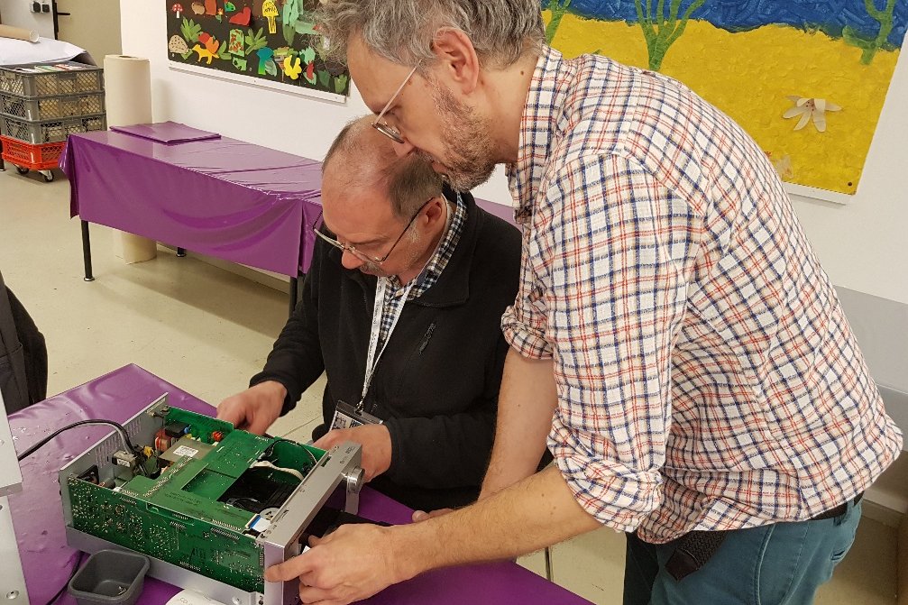 Zwei Männer reparieren einen Gegenstand im Reparaturcafé in der Statdbücherei