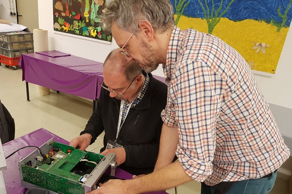Zwei Männer reparieren einen Gegenstand im Reparaturcafé in der Statdbücherei