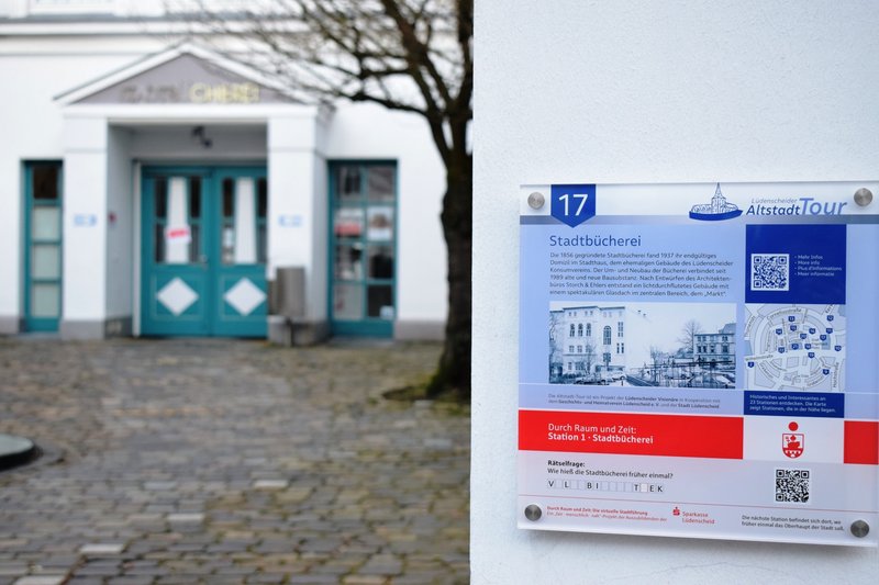 Hinweistafel an der Fassade der Stadtbücherei mit QR-Code für weitere Infos
