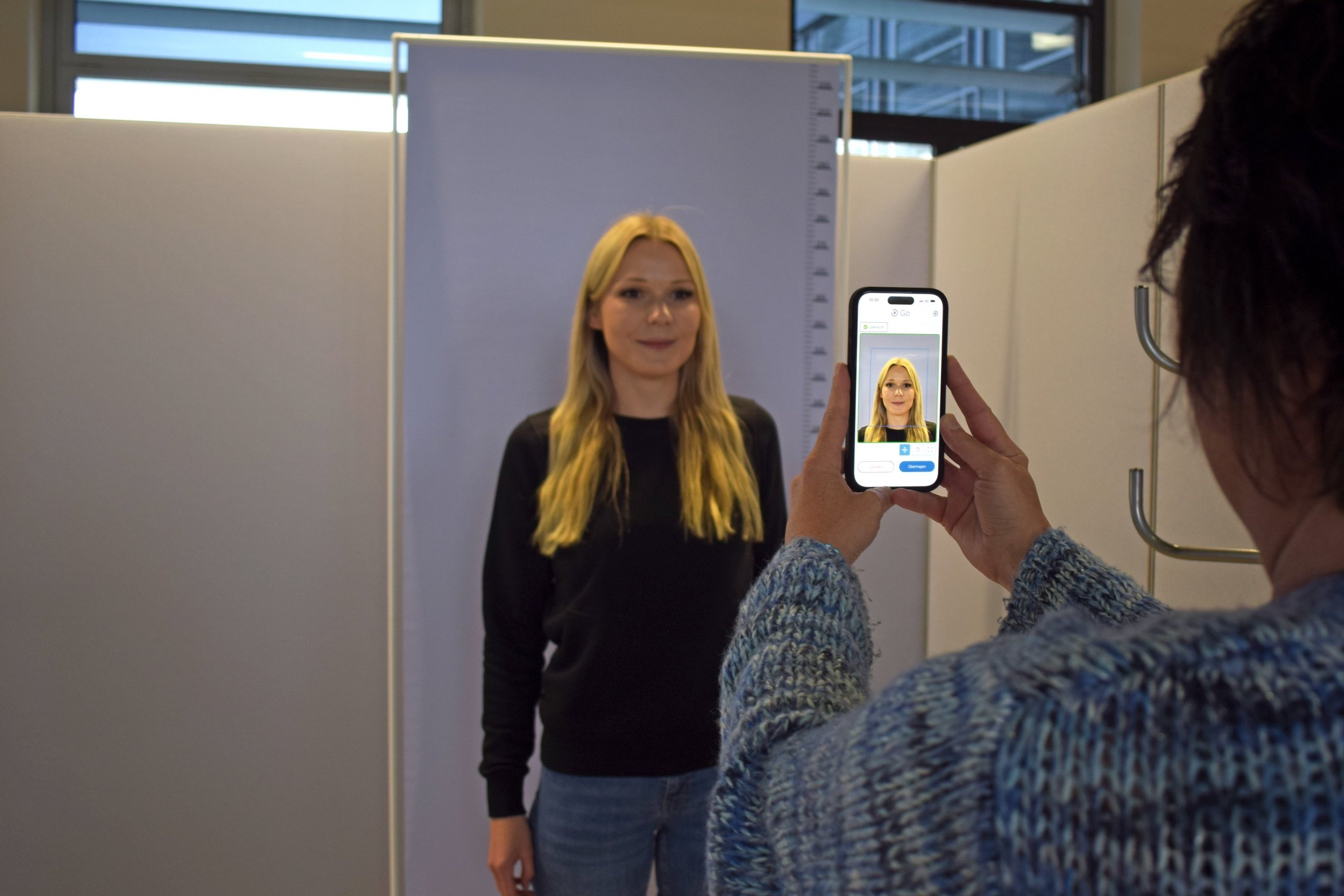 Eine Frau nimmt mit einem Handgerät ein Bild von einer anderen Frau auf.