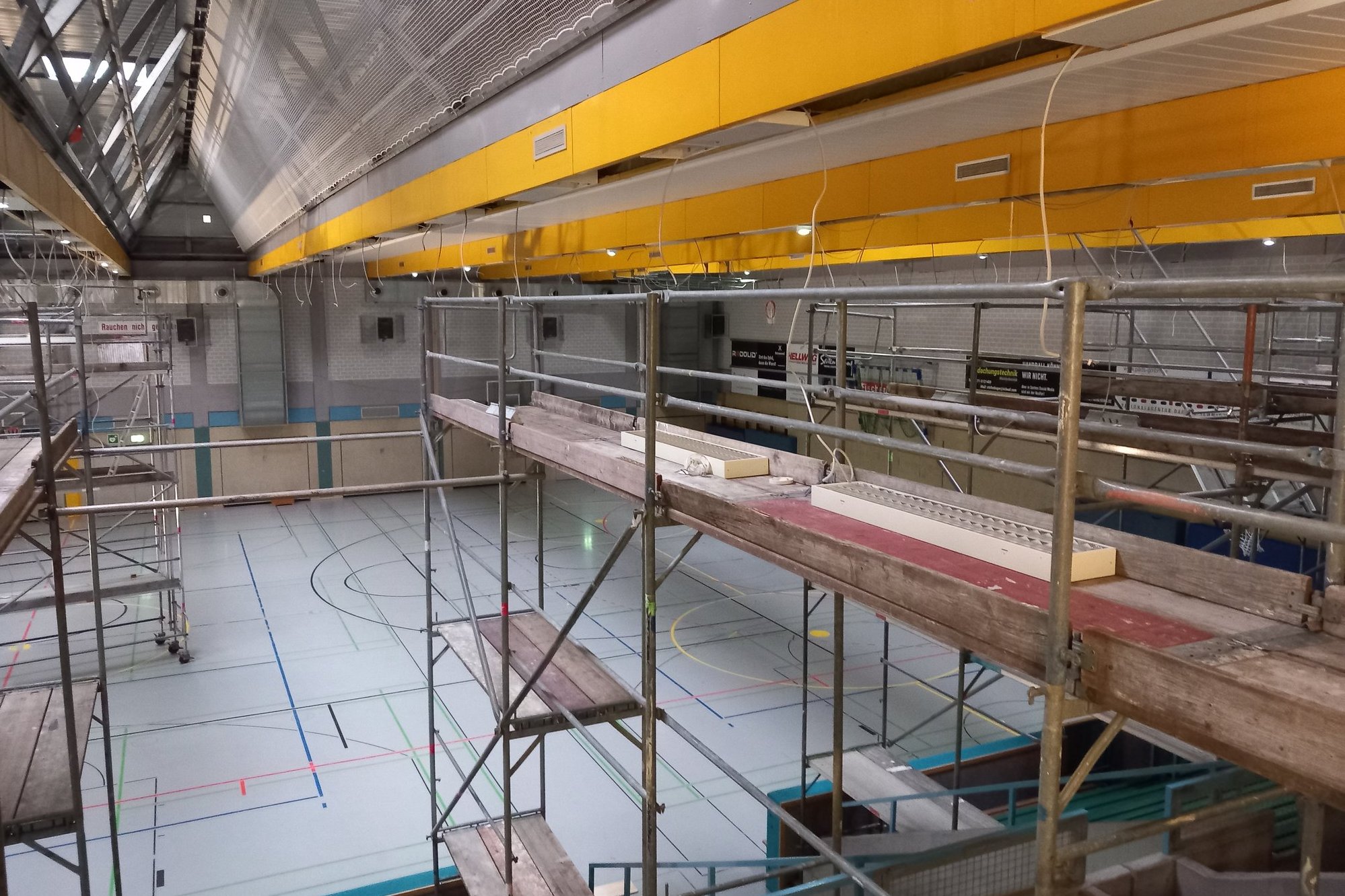 In einer Sporthalle sind Gerüste aufgebaut, die bis unter die Decke reichen.