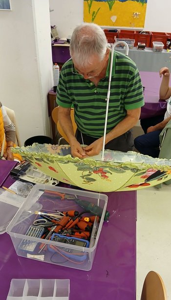 Ein Ehrenamtlicher repariert im Reparaturcafé in der Stadtbücherei einen Regenschirm