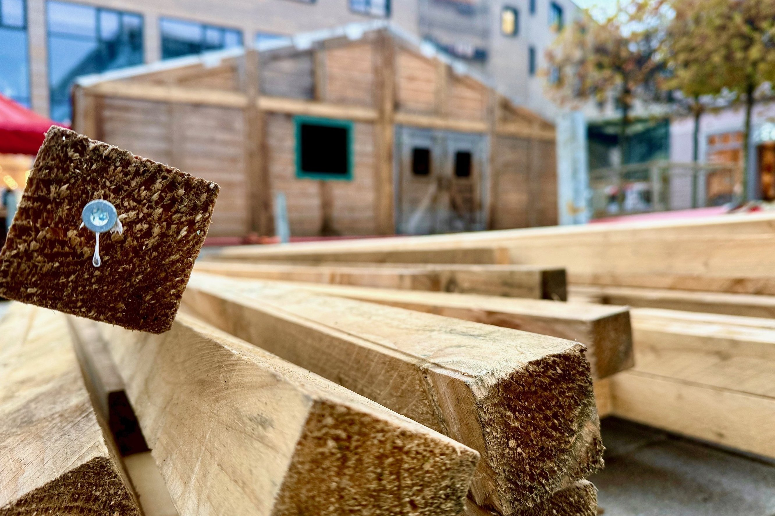 Im Vordergrund sind Holzlatten zu sehen, im Hintergrund eine Holzhütte.