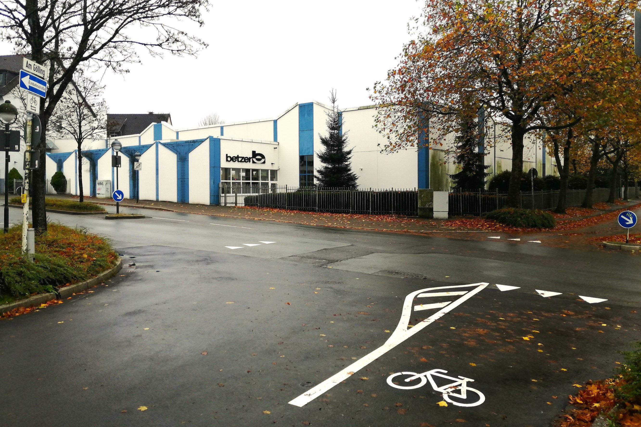 Eine Kreuzung, auf der Fahrbahnmarkierungen und ein Fahrrad-Piktogramme in weißer Farbe aufgemalt sind. 