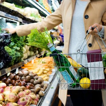 Eine Frau kauft mit einem Einkaufskorb im Supermarkt ein