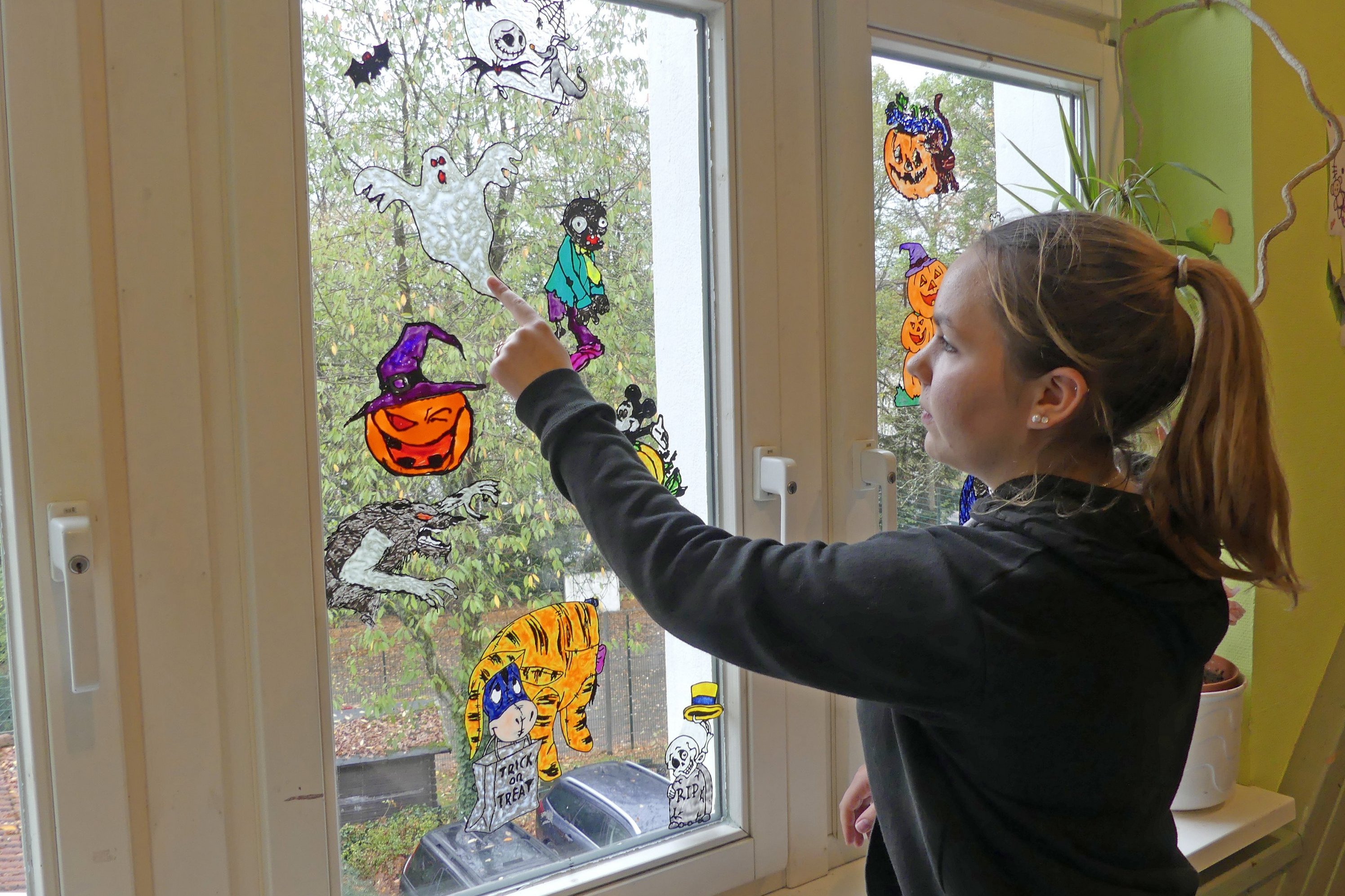 Junge Frau beklebt ein Fenster in einer Kita.