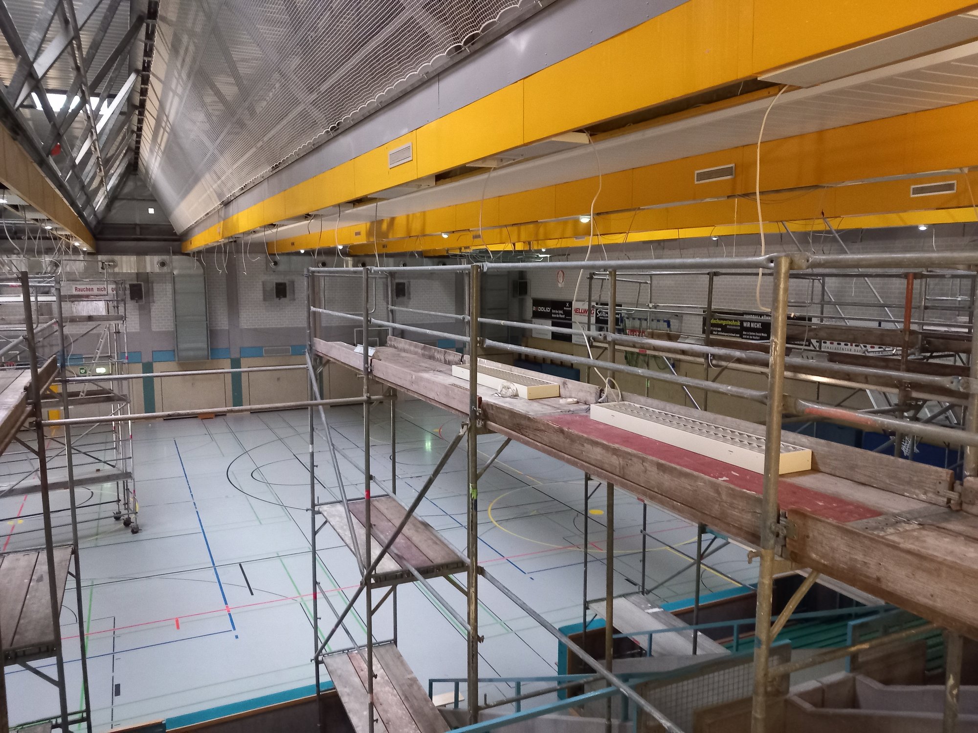 In einer Sporthalle sind Gerüste aufgebaut, die bis unter die Decke reichen.