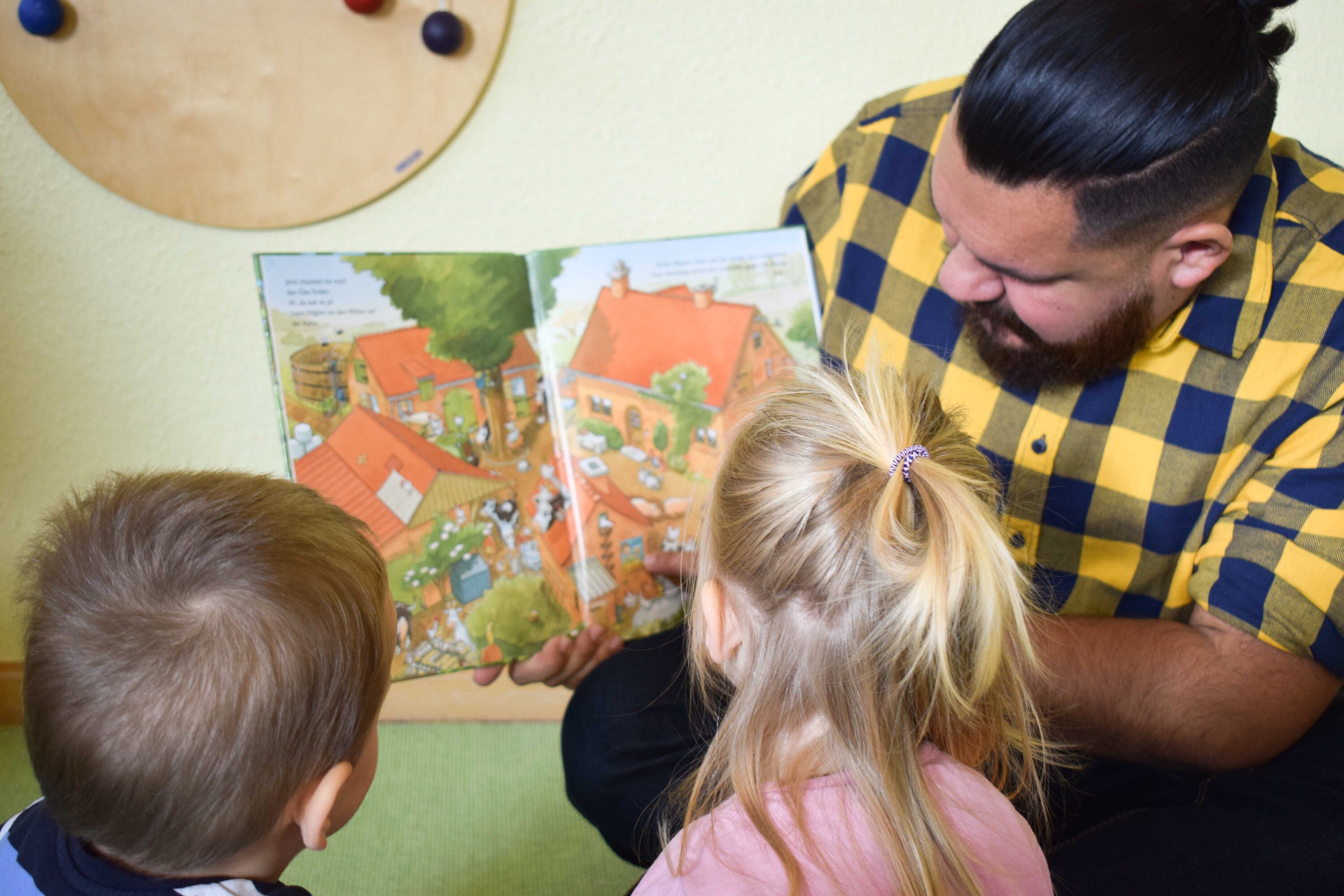 Ein Erzieher liest zwei Kindergartenkindern vor